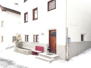 a red bench in front of a building with snow at Chasa Anguel in Samnaun