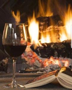a glass of wine next to a book and a fireplace at Red Rose Apartament -Parking -Taras- Faktura VAT in Kielce