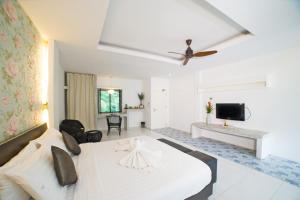 a white bedroom with a bed and a living room at Surintra Boutique Resort in Surin Beach