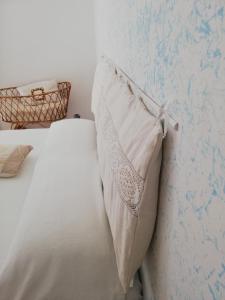 ein weißes Bett mit einem Kissen an der Wand in der Unterkunft Il Vicolo di Ripa B&b in Ripatransone