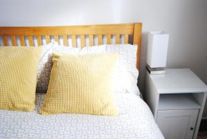 a bed with yellow and white pillows and a night stand at Ash House in Uppingham