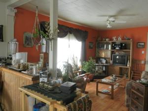 a living room with orange walls and a kitchen at Domaine Joseph Ross Bed and Breakfast in Cap-Chat