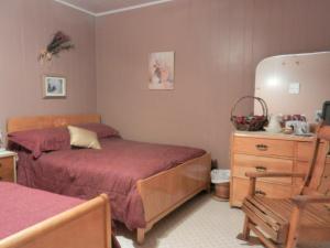 een slaapkamer met 2 bedden en een houten dressoir bij Domaine Joseph Ross Bed and Breakfast in Cap-Chat