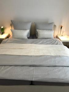 a large bed with white sheets and pillows at Ferienwohnung am Wald in Hachenburg