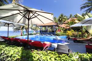a swimming pool with chairs and an umbrella at Teluk Karang Dive & Spa Resort in Tejakula