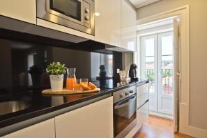 a kitchen with black and white counters and a microwave at Lisbon Finestay Mastro Apartments in Lisbon