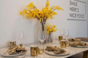 a table with plates and a vase of yellow flowers at Wuhan Jianghan·Zhongshan Park· Locals Apartment 00157640 in Wuhan