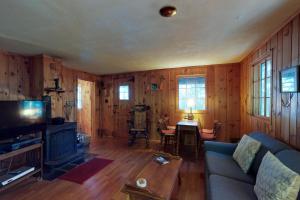 een woonkamer met houten wanden en een blauwe bank bij Traditional Maine Cabin in Greenville