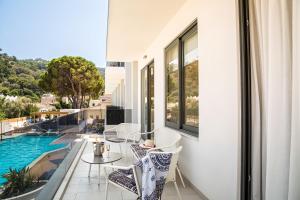 balcón con mesa, sillas y piscina en Samian Mare Hotel, Suites & Spa en Karlovasi