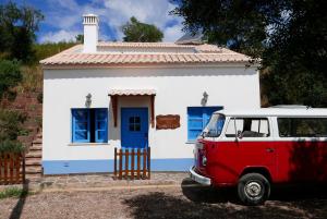 una furgoneta roja estacionada frente a una casa pequeña en Barranco do Zambujeiro, en Vila do Bispo