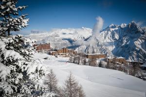 un resort en la nieve con montañas en el fondo en Arc en Ciel Les Karellis, en Montricher-le-Bochet