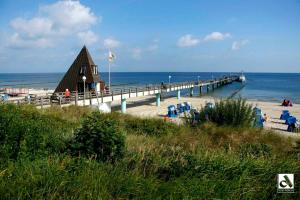 ein Pier mit Stühlen und ein Gebäude am Strand in der Unterkunft Hauptstrasse 13 DHH in Ostseebad Koserow