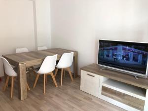 mesa de comedor con sillas blancas y TV en Apartamento Asuncion, en Benidorm