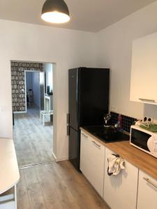 a kitchen with a black refrigerator and a counter top at Le Riva Plage Appartement in Ouistreham