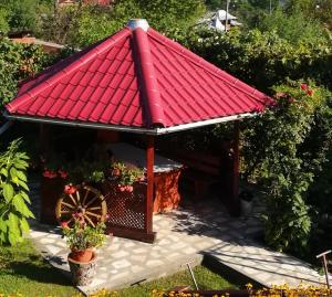 a red roofed gazebo with a wheel at Pensiunea Dana in Horezu