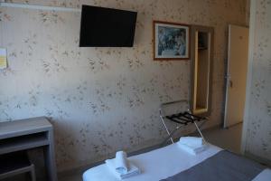 a room with a chair and a television on a wall at Hotel Pinede in Saint-Jean-de-Monts