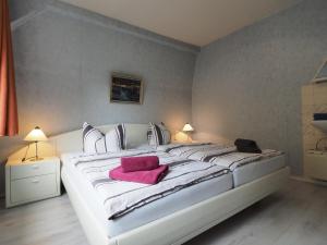 Una cama blanca grande con una toalla rosa. en Apartments Carmen, en Braunlage