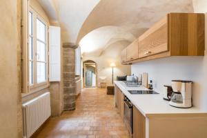 a kitchen with white countertops and a long hallway at Honorê - Suite Romain Rolland in Lyon