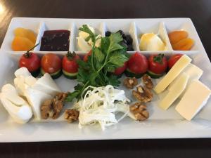 un plato blanco con diferentes tipos de queso y hortalizas en Yavuzhan Hotel, en Side