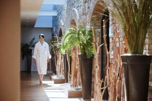 uma mulher a andar por um corredor com vasos de plantas em Farnham Estate Spa and Golf Resort em Cavan