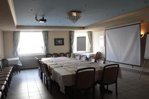 a conference room with a large table and a screen at Hotel Tannenhof in Lauterbach