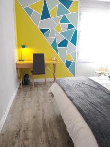 1 dormitorio con cama, escritorio y pared en Les Clés du Bonheur by Beds4Wanderlust, 47m2 avec Terrasse privative & Parking-RER B TGV 10min-Orly 20min, en Massy
