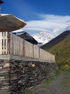 un mur en pierre avec un parasol à côté d'une montagne dans l'établissement Century House of Larisa, à Mestia