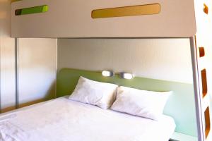 a bed with a canopy with white pillows at Hotel ibis Budget Laval in Bonchamp-lès-Laval