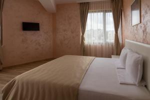 1 dormitorio con 1 cama blanca grande y ventana en Hotel Kardjali, en Kardzhali