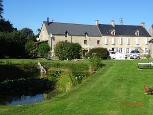a large house with a pond in front of it at La ferme aux chats in Formigny