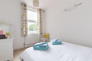Un dormitorio con una cama blanca con toallas azules. en Baker's Dozen en Stratford-upon-Avon