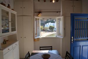 CherronisosにあるAmmos Holiday Houseのキッチン(テーブル付)、青いドア、窓が備わります。