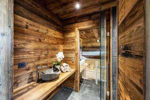 a bathroom with a wooden wall with a sink at Haus Christophorus in Mariapfarr