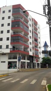 a large white building with red balconies on a street at Apartamentos Ed London, na Av principal a poucos passos das Termas in Piratuba