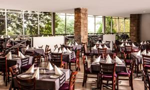 Avani Maseru Hotel في ماسيرو: غرفة طعام مع طاولات وكراسي ونوافذ
