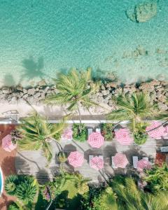 einen Luftblick auf einen Strand mit Palmen und rosa Sonnenschirmen in der Unterkunft Cobblers Cove - Barbados in Saint Peter