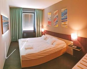 1 dormitorio con 1 cama grande con sábanas blancas en Orion Apartman, en Sárvár