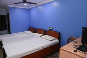 Cama en habitación con pared azul en Vani Lodge en Visakhapatnam