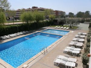 a swimming pool with lounge chairs and a hotel at Apartamentos Miami in L'Estartit