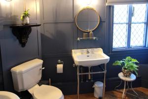 ein Badezimmer mit Waschbecken, Toilette und Spiegel in der Unterkunft Smugglers Cottage in Hastings + 37 Fotos