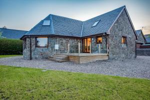 uma casa de pedra com um telhado reluzente em North Balkello Cottage em Dundee