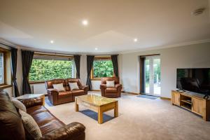 sala de estar con muebles de cuero y TV de pantalla plana en North Balkello Cottage en Dundee