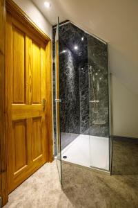 a glass shower in a room with a wooden door at North Balkello Cottage in Dundee