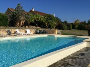 a swimming pool with chairs and a house at La Manilau in Le Buisson de Cadouin