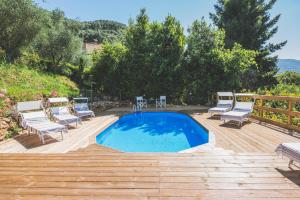 a backyard with a pool and chairs and a wooden deck at Exclusive beautiful pool house surrounded by greenery, modern, luxury finishes in Camaiore