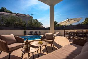 卡什泰拉Villa Filip的一个带桌椅的露台和一个游泳池