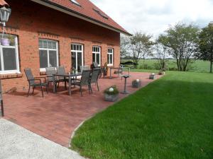 a brick patio with a table and chairs on a lawn at Landsitz Riekenshof in Horumersiel in Wangerland