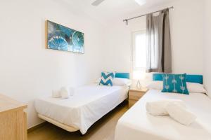 dwa łóżka w pokoju z białym i niebieskim w obiekcie Picasso Daisy w mieście Fuengirola
