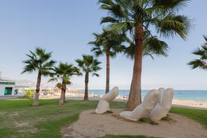 rzeźba rąk na plaży obok palm w obiekcie Picasso Daisy w mieście Fuengirola