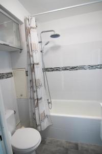La salle de bains est pourvue d'une baignoire blanche et de toilettes. dans l'établissement 5 avenue de la Gavine Résidence Hyères Parc, à Hyères